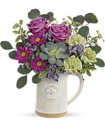 <p>Make her feel truly special with a gift as sweet and charming as she is. The Queen Bee Bouquet pairs a fresh, garden-inspired rose arrangement with a delightful bee-embossed glazed stoneware pitcher—a keepsake she’ll treasure long after the blooms have faded. The pitcher is food-safe, making it a practical and beautiful addition to her home for years to come.</p>
<p>This thoughtful bouquet features soft lavender roses, crisp green carnations, and vibrant purple daisy spray chrysanthemums, accented by delicate purple limonium. Silver dollar eucalyptus, pitta negra, and a sculptural green echeveria succulent add texture and natural elegance to complete the display.</p>
<p>Perfect for Mother’s Day, birthdays, or any occasion to celebrate the queen in your life, this bouquet blends lasting charm with heartfelt sentiment. Its blend of color, texture, and utility makes it a standout gift that brings joy and beauty to any room.</p>
<p>Each arrangement is handcrafted by skilled local florists using the freshest seasonal blooms. Some flowers may arrive in bud form to ensure longer-lasting enjoyment. Local delivery is available to bring your gift to life with care and attention.</p>
<p>Send the Queen Bee Bouquet today to brighten her day and her space with floral grace and timeless charm.</p>