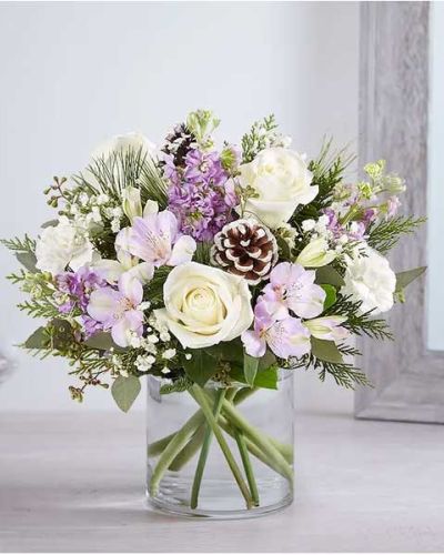 <p>Capture the quiet magic of winter with the Lovely Lavender Medley Bouquet—a serene arrangement designed to soothe the soul and warm the heart. With its soft mix of lavender and white blooms, seasonal greenery, and natural accents, this bouquet evokes the peaceful elegance of a snowy woodland scene.</p>
<p>This graceful arrangement features snowy white roses and carnations paired with lavender-hued Peruvian lilies and fragrant stock. Seeded eucalyptus and fresh holiday greenery add depth and texture, while natural pinecones bring a rustic, wintry charm. The flowers are thoughtfully arranged in a clear glass cylinder vase, creating a design that feels both modern and timeless.</p>
<p>Ideal for holiday gatherings, winter birthdays, or sending comfort and peace, this bouquet suits any occasion that calls for a gentle, heartfelt touch. Its subtle color palette and soft lines make it equally fitting for festive celebrations or as a gesture of sympathy during the colder months.</p>
<p>Each bouquet is handcrafted by skilled local florists using the freshest blooms available. Some flowers, such as the lilies, may arrive in bud form to extend the beauty of the arrangement over several days. Local delivery is available, ensuring that your gift arrives with care and seasonal charm.</p>
<p>Offered in multiple sizes to match your space or sentiment, the Lovely Lavender Medley brings quiet elegance to any table, entryway, or desk. Its calming tones and thoughtful textures offer a moment of reflection and beauty in the heart of winter.</p>
<p>Send a bouquet that speaks in soft, graceful tones—the Lovely Lavender Medley is a comforting, elegant choice for any seasonally inspired sentiment.</p>
