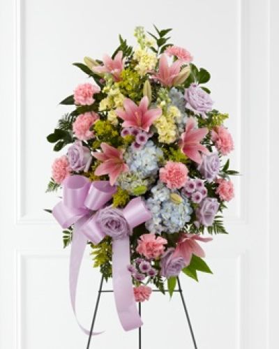 <p>Offer a gentle tribute that reflects peace, natural beauty, and heartfelt remembrance. This standing floral spray is a serene and thoughtful way to honor someone whose life was filled with quiet grace and kindness. Its soft colors and elegant composition bring comfort to those who grieve, serving as a visual reminder of love, memory, and the tender bond that remains.</p>
<p>The arrangement includes a balanced mix of lavender roses, pink carnations, Asiatic lilies, yellow stock, blue hydrangea, lavender button poms, solidago, and fresh greenery. Every stem is placed with care to create a harmonious display that captures the contrast of sorrow and gratitude. A satin ribbon in lavender completes the design, adding a refined and gentle touch to the overall presentation.</p>
<p>Perfect for funerals, memorials, or celebration of life services, this floral spray brings warmth and solace to the space it occupies. Its natural palette and tranquil textures make it ideal for remembering someone who inspired calm, generosity, or quiet joy in the lives of others. Whether honoring a family member, close friend, or beloved mentor, this tribute speaks with dignity and compassion.</p>
<p>Crafted with fresh, high-quality blooms, each arrangement is designed with a focus on emotional resonance and visual elegance. The thoughtful pairing of colors and flowers ensures that the display feels both timeless and personal, creating a meaningful experience for everyone in attendance. This tribute offers a sense of grace and support during one of life’s most tender moments.</p>
<p>Let this floral spray express what words may not fully capture. With its soft beauty and natural presence, it honors a life remembered with affection and respect. It stands as a lasting symbol of sympathy, comforting those who gather to say goodbye.</p>