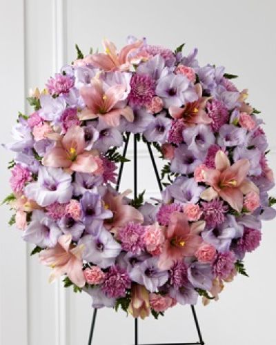 <p>When words are not enough, flowers offer a quiet way to express love, gratitude, and remembrance. This elegant wreath is a gentle and heartfelt tribute to someone who brought warmth and kindness into the lives of others. With soft tones of pink and lavender, it creates a visual message of friendship, affection, and enduring memory during a time of loss.</p>
<p>The arrangement includes a graceful blend of lavender gladiolus, pink lilies, blush carnations, and seasonal accents, all placed thoughtfully within a circular frame of greenery. The shape itself speaks to the unbroken bonds of love and the lasting nature of shared memories. Each bloom contributes to a sense of calm, offering both beauty and comfort to those gathered in mourning.</p>
<p>This wreath is especially meaningful for honoring a dear friend, close relative, or anyone remembered for their gentle heart and generous spirit. It serves not only as a floral tribute but also as a symbol of connection between those who grieve and the one they have lost. Whether displayed beside a casket or near an altar, it becomes a point of reflection and peace for everyone in attendance.</p>
<p>Crafted with care and attention to detail, each wreath is made with fresh flowers selected for their color, quality, and symbolism. The floral components are arranged to ensure a sense of natural elegance, creating a tribute that feels both personal and universally touching. This arrangement offers a respectful and loving gesture in a time that calls for quiet strength and shared support.</p>
<p>Let this wreath provide comfort and a lasting expression of remembrance. Its soft colors and circular form convey a message of never-ending love, bringing light and beauty to a day filled with reflection. For those seeking a gentle and sincere way to honor someone special, this tribute offers a meaningful presence at any farewell.</p>