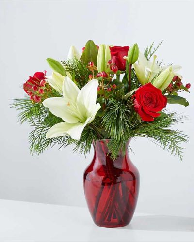 <p>Inspired by the lush greenery and timeless charm of majestic evergreens, the Evergreen Delight Bouquet brings the natural beauty of winter indoors with a look that’s both classic and fresh. This elegant arrangement captures the spirit of the season with a sophisticated blend of textures and colors that evoke warmth, comfort, and enduring style.</p>
<p>A rich mix of deep green evergreen branches is paired with carefully selected seasonal blooms, offering a subtle palette of soft, wintry hues. Arranged in a vibrant red vase that adds a festive pop of color, this bouquet balances natural greenery with delicate floral accents for a display that’s as refined as it is inviting. From the soft pine needles to the graceful seasonal touches, every element is designed to create a harmonious and memorable centerpiece.</p>
<p>Perfect for holiday gatherings, winter décor, or simply sending a thoughtful gift, the Evergreen Delight Bouquet suits any occasion during the colder months. Its classic green-and-red combination brings a festive feel without being overpowering, making it ideal for those who appreciate understated elegance with a seasonal twist.</p>
<p>Each bouquet is handcrafted by skilled local florists using the freshest greenery and flowers available. Some blooms may arrive in bud form to ensure long-lasting enjoyment. Local delivery is available to ensure your gift arrives beautifully arranged and ready to be admired.</p>
<p>Send the Evergreen Delight Bouquet today to share the peaceful beauty of winter and the timeless charm of seasonal greenery.</p>