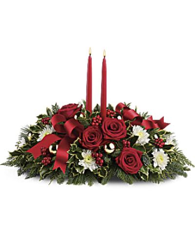 <p>Set the table for unforgettable holiday moments with the Holiday Shimmer Centerpiece. Designed to dazzle from every angle, this festive arrangement combines glowing candlelight, fresh seasonal greens, and classic Christmas florals to create a warm, joyful centerpiece filled with holiday spirit.</p>
<p>At the heart of the arrangement are elegant red taper candles that cast a soft, inviting glow. Surrounding them are fresh red roses and white cushion spray chrysanthemums, accented with red berries, gold ornament balls, and festive holiday ribbon. Lush greenery—including noble fir, white pine, flat cedar, and variegated holly—adds fullness, texture, and the familiar scent of the season. Every detail is carefully arranged to bring harmony, tradition, and cheer to the holiday table.</p>
<p>Perfect for Christmas dinners, family celebrations, or seasonal events, the Holiday Shimmer Centerpiece makes a beautiful focal point on dining tables, buffets, or entryways. Its low, wide design ensures conversation flows easily while adding a festive touch that elevates any setting. The blend of red, white, green, and gold captures the timeless colors of the season with elegance and joy.</p>
<p>Each centerpiece is handcrafted by local florists using the freshest blooms and evergreens available. Local delivery is available to ensure your gift arrives fresh, festive, and ready to impress.</p>
<p>Send the Holiday Shimmer Centerpiece today and bring a glowing symbol of togetherness, beauty, and seasonal celebration into someone’s home.</p>