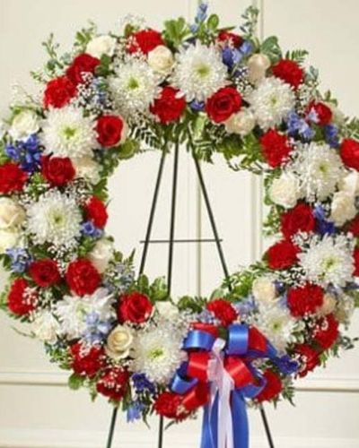 <p>Honor the life and service of a beloved veteran or patriot with a tribute that reflects courage, devotion, and national pride. The Serene Sympathies Standing Wreath in red, white, and blue is a dignified expression of remembrance, handcrafted to offer comfort and gratitude during a time of loss.</p>
<p>This striking wreath features a patriotic blend of fresh red and white roses, vivid blue delphinium, and lush greenery. Designed in a traditional circular shape and displayed on a standing easel, the arrangement symbolizes eternal love and the lasting impact of a life dedicated to family, country, and community.</p>
<p>Perfect for delivery to funeral homes by family, friends, or business associates, this wreath is especially meaningful for military services, memorials, or honoring those who proudly served. The red, white, and blue palette pays tribute to their strength, sacrifice, and honor.</p>
<p>Each Serene Sympathies Standing Wreath in red, white, and blue is handcrafted by expert florists with care and attention to detail. Same-day delivery is available to local funeral homes and memorial venues, ensuring your tribute arrives fresh, elegant, and respectfully arranged.</p>
<p>Add a personal message at checkout to share your condolences. Let this patriotic wreath serve as a lasting symbol of appreciation, remembrance, and heartfelt support.</p>