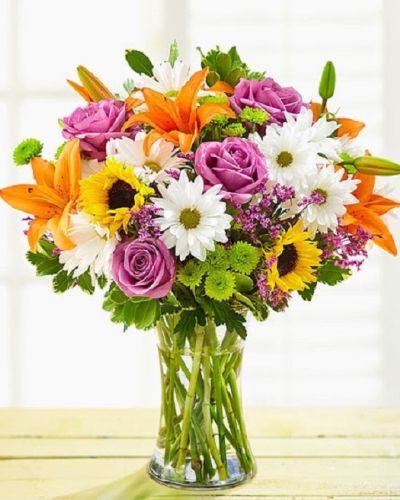 <p>Brighten someone’s day with a vibrant and uplifting bouquet designed to deliver happiness with every petal. Bursting with a cheerful mix of garden favorites, this lively arrangement is perfect for birthdays, congratulations, thank-you gestures, or simply reminding someone how much they’re loved—no special occasion required.</p>
<p>This joyful bouquet features a radiant mix of fresh roses, lilies, sunflowers, button poms, and other seasonal blooms, all hand-selected for their bold colors and playful textures. The variety of shapes and hues creates a dynamic, eye-catching presentation that instantly lifts the mood and brings warmth to any room. Every stem is arranged with care into a stylish glass vase that complements the flowers without stealing the spotlight.</p>
<p>This bouquet is a versatile favorite—ideal for surprising friends, celebrating accomplishments, or sending spontaneous joy. With its bright palette and full, rounded design, it’s sure to make a memorable impression that feels both thoughtful and fun.</p>
<p>Each bouquet is handcrafted by expert florists, made fresh to order and delivered with care. Same-day delivery is available to ensure your cheerful surprise arrives on time and in perfect bloom.</p>
<p>Add a personal message at checkout to make your gift even more meaningful. With this bouquet, you’re not just sending flowers—you’re sending joy, color, and a heartfelt moment that lasts. Let happiness bloom in full color.</p>