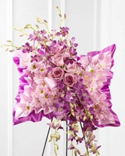 <p>Offer a sense of calm and grace during life’s most difficult moments with a floral tribute designed to reflect quiet reverence and enduring love. This elegant floral pillow is more than just an arrangement—it is a symbol of serenity and heartfelt remembrance, bringing a peaceful presence to any final farewell. Its soft hues and delicate composition make it a gentle expression of sympathy, especially when words feel out of reach.</p>
<p>A tranquil blend of lavender daisies, purple dendrobium orchids, and soft lavender roses are artfully arranged on a satin pillow, creating a design that radiates peaceful elegance. The layered textures and calming colors evoke a feeling of stillness and reflection, while the pillow itself adds an element of tenderness and support. Displayed on a wire easel, this tribute serves as a comforting and graceful focal point at any memorial gathering.</p>
<p>This floral pillow is a meaningful choice for honoring someone known for their gentle soul, artistic spirit, or quiet strength. Its subtle palette and refined design make it appropriate for a variety of relationships and settings—from close friends and extended family to colleagues and mentors. The arrangement’s soft visual language communicates love and respect in a deeply personal way.</p>
<p>Each piece is thoughtfully arranged with fresh, premium blooms to ensure that your sentiment is conveyed with beauty and care. The plush satin base adds to the sense of softness, while the flowers are chosen not only for their color but also for their symbolism—offering peace, remembrance, and affection. This arrangement brings a moment of tranquility into spaces filled with emotion, offering comfort through thoughtful design.</p>
<p>Let this elegant floral pillow honor the life of someone dearly missed. With its gentle presence and poetic simplicity, it becomes a visual embrace of calm, love, and quiet strength—offering solace to the grieving and celebrating a life remembered with tenderness.</p>