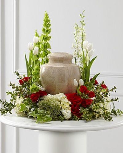 <p>Express deep sympathy with this elegant floral arrangement designed to surround an urn with warmth, beauty, and grace. Its lush blend of classic reds, pure whites, and vibrant greens offers comfort during difficult moments while honoring the legacy of someone dearly missed.</p>
<p>This exquisite tribute features a rich variety of premium blooms, including vivid red roses and red spray roses for heartfelt emotion, paired with the quiet purity of white tulips and hydrangea. White larkspur and trachelium add height and airiness, while bright green Bells of Ireland bring movement and a symbolic message of renewal. Accents of hypericum berries, ivy, and myrtle provide depth and natural elegance, completing a design that comforts and inspires.</p>
<p>Carefully designed to encircle an urn or framed photo, this arrangement creates a serene and beautiful focal point at memorial services or celebrations of life. The combination of colors and textures evokes memories, love, and spiritual peace, supporting and uplifting those gathered in remembrance.</p>
<p>Each arrangement is crafted with compassion and care by experienced local florists. Delivered promptly and professionally, same-day service is available with coordination through funeral homes or service venues to ensure seamless delivery.</p>
<p>Add a personalized message during checkout to accompany your tribute with words of comfort. This arrangement is more than flowers—it is a meaningful expression of love, remembrance, and heartfelt support during times of loss.</p>