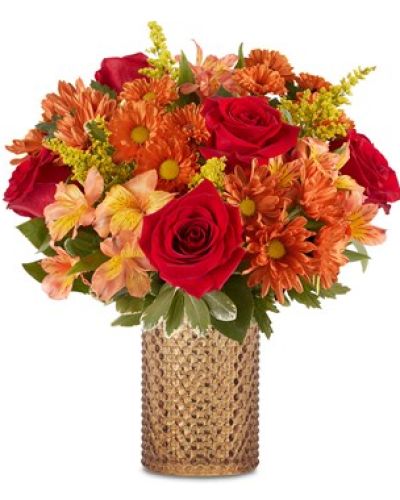 <p>Celebrate the cozy brilliance of autumn with a bouquet that radiates warmth, charm, and seasonal color. This rustic arrangement captures the essence of fall with its richly hued blooms and nostalgic appeal, making it a lovely choice for heartfelt gifts or seasonal home décor. Whether you’re sending a thoughtful message or simply embracing the season, it delivers beauty in every detail.</p>
<p>The bouquet features a glowing mix of orange roses, golden sunflowers, bronze mums, and warm-toned carnations. Each flower is chosen for its color, texture, and freshness, blending into a harmonious display that echoes the beauty of a golden autumn landscape. Seasonal greenery adds fullness and contrast, giving the design depth and a natural, gathered feel.</p>
<p>Presented in a vintage-style amber glass vase with a textured finish, the arrangement offers both elegance and rustic charm. The keepsake container adds lasting value, perfect for displaying future arrangements or adding character to seasonal vignettes. Its warm amber tone complements the autumnal palette and makes it a standout decorative piece.</p>
<p>This bouquet is a thoughtful choice for birthdays, thank-you gifts, housewarmings, or holiday gatherings. It’s especially fitting as a hostess gift or seasonal centerpiece, bringing the comfort and richness of fall indoors with ease. Its inviting colors and timeless styling make it suitable for casual and formal settings alike.</p>
<p>Each arrangement is hand-designed using fresh, seasonal blooms and delivered with care. While substitutions may occur due to availability, the look and feel of the bouquet will always reflect the same rustic radiance and fall-inspired elegance. Share the spirit of the season with a floral gift that glows with warmth and joy.</p>