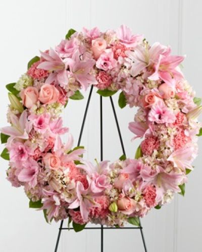 <p>In moments of grief, flowers can express what words cannot. This delicate wreath offers a gentle and dignified way to honor a life filled with warmth, compassion, and grace. Formed in the shape of a circle, it symbolizes the continuity of love, the beauty of remembrance, and the eternal bond shared with someone deeply missed.</p>
<p>A graceful mix of soft pink roses, fragrant Oriental lilies, elegant gladiolus, full hydrangea, and delicate carnations are thoughtfully arranged with fresh, verdant greenery. Every bloom is chosen to reflect tenderness and respect, creating a design that is visually soothing and emotionally resonant. Displayed on a sturdy wire easel, the wreath becomes a touching focal point at any memorial or farewell ceremony.</p>
<p>The soft pink palette of this tribute speaks to gentleness, admiration, and affection, making it a particularly meaningful choice for remembering mothers, daughters, grandmothers, or close friends. Whether offered by family, extended relatives, or longtime friends, this floral tribute serves as a comforting expression of shared love and deep appreciation for a life well lived.</p>
<p>Each arrangement is crafted with care to ensure it honors the occasion with both beauty and sentiment. The floral elements are selected not only for their appearance but also for their symbolism—offering a message of serenity and strength to those mourning the loss of someone dear. It’s a heartfelt way to extend comfort while celebrating cherished memories.</p>
<p>Let this wreath be a quiet yet powerful gesture of sympathy, standing as a symbol of eternal love and remembrance. In its gentle presence, it brings comfort to the grieving and serves as a lasting tribute to a soul that touched many lives.</p>