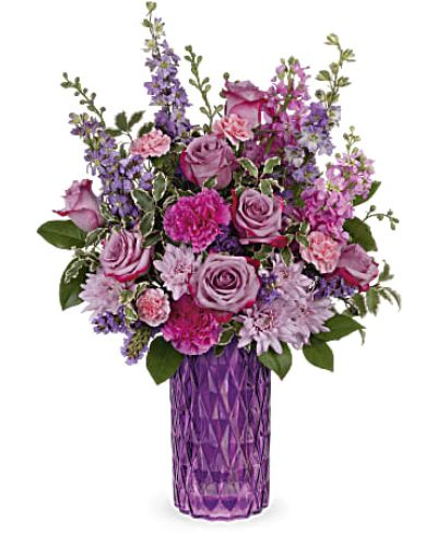 <p>Elevate any moment from ordinary to extraordinary with a bouquet that dazzles in shades of lavender, pink, and violet. Refined, radiant, and rich in detail, this arrangement is designed to pamper and impress—making it a stunning choice for Mother’s Day, birthdays, or any heartfelt celebration. Its graceful colors and textures deliver a lasting impression with elegance and warmth.</p>
<p>This luxurious design features a lush combination of lavender roses, purple larkspur, soft pink stock, and rich purple carnations. Lavender cushion chrysanthemums and miniature pink carnations add texture and depth, while accents of purple statice, lemon leaf, and pitta negra bring balance and a touch of natural greenery. The result is a bouquet filled with movement, harmony, and refined charm.</p>
<p>Arranged in a jewel-toned, diamond-cut glass vase, the bouquet glows in soft light and offers timeless sophistication. The vase’s faceted design adds a keepsake element to the gift, offering beauty long after the flowers have faded. Together, the blooms and vase create a striking centerpiece or thoughtful gift for someone truly special.</p>
<p>Ideal for expressing love, admiration, or appreciation, this bouquet suits a variety of occasions and recipients. Its classic palette and vintage-inspired style appeal to all ages, while the fragrance and fullness of the blooms bring a sense of comfort and celebration. Whether it’s a milestone moment or a spontaneous surprise, this arrangement delivers heartfelt meaning in every petal.</p>
<p>Each bouquet is handcrafted by a skilled florist and delivered fresh with care. Seasonal variations may affect the exact mix of flowers, but the overall color harmony and elegance remain constant. Give the gift of beauty, fragrance, and timeless design—a floral gesture that turns any day into something unforgettable.</p>