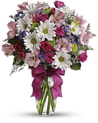 <p>Some bouquets feel like sunshine in a vase—and this one is no exception. With its soft colors, playful spirit, and effortless charm, this arrangement is a lovely way to lift someone’s mood and share a heartfelt message. Whether you’re offering thanks, celebrating a milestone, or simply making someone’s day a little brighter, it speaks with grace and warmth.</p>
<p>The bouquet blends fresh roses and seasonal blooms in a palette of soft pinks, lively purples, and lush greens. Each flower is selected for its vibrancy and texture, creating a colorful mix that feels both sweet and polished. Presented in a clear glass vase and finished with a lavender ribbon, the design is cheerful, elegant, and ready to brighten any room.</p>
<p>This versatile bouquet is ideal for birthdays, get-well wishes, thank-you gifts, or those spontaneous “just because” moments. Its joyful tones and classic styling make it a thoughtful choice for friends, coworkers, partners, or family members alike. No matter the reason, it delivers beauty and sentiment with every petal.</p>
<p>Handcrafted by a skilled florist and delivered with care, each arrangement is made using the freshest blooms available. Natural variations in flower types may occur with the seasons, but the soft palette and uplifting feel will always remain. Some stems may arrive in bud form, offering longer enjoyment as the flowers open gradually.</p>
<p>Send a little sweetness with a bouquet that’s lighthearted, lovely, and full of heart—a charming floral gift that shares your feelings with effortless beauty.</p>