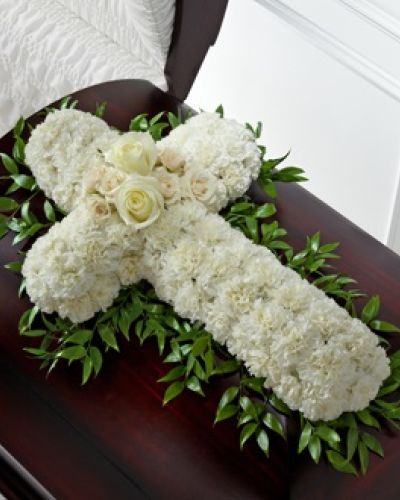 <p>Honor a life rooted in faith and love with this striking casket spray designed in the shape of a cross. This floral display offers a heartfelt message of spiritual devotion, eternal peace, and cherished memories. It provides a comforting and meaningful way to say goodbye while expressing deep love and respect.</p>
<p>Soft white roses and spray roses create a graceful focal point at the center, while pure white carnations form the full shape of the cross. Lush greenery accents the sides, adding contrast, texture, and natural elegance. Carefully crafted to rest atop the casket, this arrangement brings quiet strength and spiritual presence to the service.</p>
<p>The white cross symbolizes peace, purity, and the hope of eternal life, making this spray ideal for religious services, memorials, or celebrations of life. It offers comfort to the family and all who gather to honor a life well lived.</p>
<p>Each arrangement is made fresh to order by compassionate florists and delivered with care. Coordination with local funeral homes ensures timely and respectful service. Same-day delivery is available in the area to provide dependable support during difficult times.</p>
<p>Add a personal message during checkout to accompany your tribute with care. This casket spray offers a reverent and beautiful way to remember someone who lived with grace and faith, symbolizing lasting peace and devotion.</p>