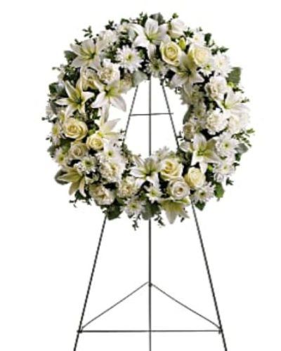 <p>Honor the gentle spirit of a loved one with a timeless wreath that symbolizes eternal love and remembrance. Composed of soft white blossoms and soothing greenery, this standing wreath offers comfort and calm during times of sorrow. It is a thoughtful expression of sympathy, perfectly suited for funeral services, wakes, or memorial gatherings.</p>
<p>This elegant wreath features a harmonious blend of white roses, Asiatic lilies, carnations, and chrysanthemums—each chosen for their symbolic purity, love, and reverence. The floral ring is accented with lush greens including salal, oregonia, and dusty miller, adding texture and natural beauty to the design. Mounted on a wire easel, the arrangement stands tall and dignified as a focal point of remembrance.</p>
<p>The circular shape of the wreath represents eternity and the continuity of love, making it a meaningful tribute for honoring a parent, grandparent, or dear friend whose memory will forever remain in the hearts of those they touched.</p>
<p>Each wreath is handcrafted with care by expert florists. Same-day delivery is available to funeral homes and memorial venues to ensure your tribute arrives fresh and respectfully presented.</p>
<p>Include a personal message at checkout to share your thoughts, love, or condolences. Express sympathies with flowers that offer comfort and reflect the beauty of a life remembered. This wreath is a graceful expression of love, peace, and remembrance.</p>