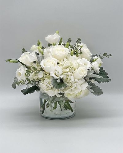 <p>Make a lasting impression with an all-white bouquet that exudes elegance, purity, and calm. Perfect for life’s most meaningful moments, this stunning arrangement offers a sophisticated way to express love, sympathy, appreciation, or simply a thoughtful “thinking of you.”</p>
<p>The bouquet features a radiant mix of fresh white blooms such as roses, lilies, hydrangeas, and spray chrysanthemums, each carefully selected for their beauty and serene presence. Accented with soft greenery and arranged in a classic glass vase, the composition presents a clean, polished look that feels both modern and timeless.</p>
<p>This arrangement is an ideal gift for weddings, anniversaries, sympathy tributes, or celebrating new beginnings. Its neutral color palette brings light and peace to any setting, making it a versatile and heartfelt choice that conveys sincere emotions with grace.</p>
<p>Each bouquet is handcrafted with care by skilled floral designers who ensure every bloom is fresh and beautifully arranged. Prepared and delivered promptly, the arrangement arrives fragrant and ready to offer comfort and warmth. Personalized messages can be added at checkout to accompany this graceful gift and deepen its meaning.</p>
<p>Sending this bouquet means offering more than flowers—you share a sincere gesture of warmth and thoughtfulness. It stands as a lasting symbol of purity and elegance, perfect for honoring life’s tender moments with quiet beauty.</p>