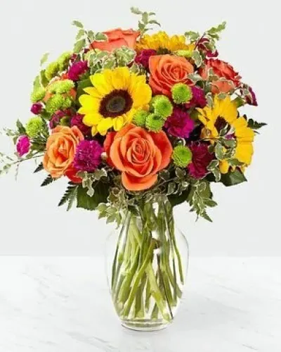 The Color Craze Bouquet blooms with a vibrant energy to create a special moment for your recipient! Our floral professionals weave together a blend of orange roses, sunflowers, violet mini carnations, green button poms, and lush greens to create an incredible gift. Presented in a clear glass vase, this truly colorful display of fresh flowers is ready to send your warmest birthday, thank you, or get well wishes straight to their door.

STANDARD bouquet is approx. 15H x 12W.
DELUXE bouquet is approx. 15H x 13W.
PREMIUM bouquet is approx. 16H x 14W.