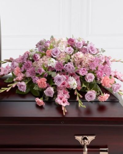<p>This elegant casket spray brings soft beauty and tender comfort to honor the memory of a beloved individual. Carefully composed with lavender roses, chrysanthemums, and parrot tulips, the arrangement creates a soothing palette that reflects grace and serenity. These blooms are thoughtfully combined with pink carnations, gladiolus, stock, hydrangea, and rich greenery, resulting in a harmonious design full of texture, depth, and gentle color.</p>
<p>Designed specifically to adorn the top of a casket, this tribute serves as a heartfelt expression of love and remembrance. Each flower is chosen not only for its beauty but also for the meaning it conveys—lavender roses symbolize grace and tranquility, while pink carnations speak to admiration and affection. The lush greenery and varied blooms bring life and warmth to the arrangement, creating a comforting presence at a solemn farewell.</p>
<p>This casket spray honors the life and legacy of the departed by providing a visual expression of sympathy and respect. It helps convey emotions that words alone cannot capture, offering solace to family and friends during a time of loss. Its elegant design and thoughtful composition ensure it will be a fitting tribute that celebrates a life well lived and cherished memories that endure.</p>