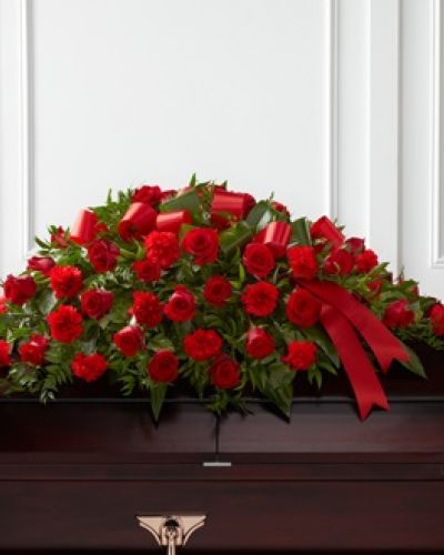 <p>Celebrate a life lived with love and strength through this striking casket spray, a rich arrangement of red blooms that honors the memory of someone deeply cherished. Designed to rest atop the casket, this bold and elegant spray conveys deep affection, heartfelt remembrance, and lasting respect.</p>
<p>The arrangement features classic red roses and red carnations, symbols of devotion and admiration. These vibrant blooms are nestled within lush greenery, creating depth, texture, and graceful flow that complement the rich tones. A red satin ribbon completes the piece, adding a polished and dignified touch that ties the tribute together.</p>
<p>This casket spray serves as an ideal centerpiece for funeral services, memorials, or celebrations of life. Its rich red palette is timeless and meaningful, expressing love, legacy, and emotional depth. Whether chosen by family or close friends, it offers a powerful final tribute that reflects the passion and vitality of a well-lived life.</p>
<p>Each arrangement is handcrafted with care and made fresh to order. Delivery is coordinated with local funeral homes and venues to ensure respectful and timely presentation. Same-day delivery is available throughout the area.</p>
<p>Add a personal message during checkout to accompany your floral tribute. Whether honoring a parent, partner, sibling, or friend, this casket spray helps you say goodbye with beauty, strength, and grace.</p>
