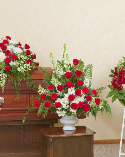 <p>Honor a life lived with passion, dignity, and love through a coordinated display that reflects both strength and serenity. This refined trio offers red and white floral arrangements designed to bring peace and remembrance to any funeral or memorial service.</p>
<p>The tribute set includes a red and white casket spray, a matching floral urn arrangement, and a circular standing wreath. Each piece features bold red roses, white lilies, carnations, and complementary greenery—symbols of devotion, respect, and lasting love. Together, they create a cohesive and heartfelt tribute that speaks volumes without words.</p>
<p>Ideal for family members organizing a full-service memorial, this trio honors someone whose presence was both powerful and deeply cherished. The red and white color palette represents a balance of courage and compassion, making this an especially meaningful choice.</p>
<p>Each arrangement is handcrafted by experienced florists who ensure every detail arrives fresh, unified, and respectfully arranged. Careful attention is given to create a lasting and elegant memorial.</p>
<p>Add a personalized message to accompany this beautiful tribute. This floral trio allows you to honor a loved one’s memory with grace, elegance, and enduring love.</p>