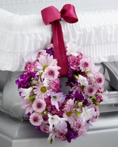 <p>When words cannot fully express your feelings, a gentle floral tribute can convey deep sympathy and love. This small yet striking wreath adornment offers a tender expression of heartfelt prayers and eternal remembrance in a subtle but meaningful way.</p>
<p>Measuring six inches, the wreath features a calming blend of lavender carnations, soft daisies, button poms, and elegant freesia. Each flower is thoughtfully selected to symbolize peace, affection, and grace. Deep magenta stock adds rich contrast, reflecting the depth of emotion during times of loss. Suspended from a burgundy wired ribbon, the wreath hangs gracefully from the side of a casket, adding a personal and loving detail to the memorial setting.</p>
<p>More than a simple floral arrangement, this wreath serves as a quiet reminder of the circle of life, the continuity of memory, and the gentle presence of those who have passed. It complements larger sprays and stands without overwhelming the space, making it a fitting tribute for families seeking to add meaningful symbolism to funeral services or memorial gatherings.</p>
<p>Ideal for traditional ceremonies, celebrations of life, and intimate family remembrances, this wreath brings comfort and thoughtfulness to farewells. Whether honoring a parent, sibling, or close friend, it offers a beautifully subtle way to express lasting affection and respect.</p>
<p>Carefully crafted and delivered with sensitivity, this wreath arrives fresh and thoughtfully arranged, allowing you to focus on honoring your loved one. It is a graceful way to share your thoughts and prayers when words alone cannot suffice.</p>