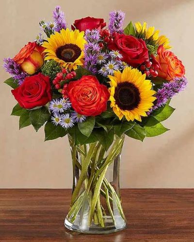 <p>Capture the heart of the season with a bouquet that brings rustic joy and golden warmth into any space. Inspired by the peaceful charm of the countryside, this autumn arrangement is filled with vibrant color and cozy texture, perfect for celebrating life’s simple pleasures. It’s a heartfelt way to brighten someone’s day with the beauty of fall in full bloom.</p>
<p>The bouquet overflows with rich orange roses, golden sunflowers, bronze daisies, deep red carnations, and golden solidago. Fresh greenery adds contrast and fullness, while the arrangement is presented in a country-inspired vase or basket that enhances its natural, down-to-earth appeal. Each bloom is hand-selected for seasonal freshness and radiant color, creating a design that feels like a crisp walk through an autumn garden.</p>
<p>Ideal for birthdays, anniversaries, fall weddings, or thoughtful gestures “just because,” this bouquet adds warmth to any occasion. Its cheerful palette and rustic style make it a welcoming centerpiece or a lovely gift for someone who appreciates the colors and textures of the season.</p>
<p>Each arrangement is handcrafted with care by a skilled florist and delivered fresh with your personal message. While flower types or containers may vary slightly due to seasonal availability, the overall look and harvest-inspired charm will always remain. This thoughtful attention ensures every bouquet feels personal and unique.</p>
<p>Celebrate fall’s beauty with a gift that brings comfort, color, and connection. Whether it’s placed in a kitchen, living room, or entryway, this bouquet fills the space with joy and the unmistakable feeling of home.</p>