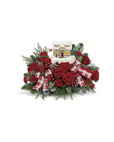 <p>Bring the magic of a snowy village scene into any home with a bouquet that captures the heart of the holiday season. This festive arrangement combines seasonal beauty with old-fashioned charm, making it a perfect gift for celebrating traditions and creating new memories. With its rich colors and cozy presentation, it delivers warmth, nostalgia, and joy in every petal.</p>
<p>At the center of this holiday display is a cheerful mix of deep red spray roses, standard carnations, and miniature red carnations. These blooms are surrounded by lush greenery, including noble fir, cedar, white pine, seeded eucalyptus, and soft dusty miller. The result is a fragrant and textural bouquet that feels like a walk through a winter forest—fresh, colorful, and full of Christmas spirit.</p>
<p>The flowers are arranged in a collectible keepsake container styled as a quaint candy shop, complete with hand-painted detailing and a soft internal glow. This ceramic village piece adds a whimsical touch to holiday décor and can be displayed year after year. Once the blooms have faded, the container continues to bring festive charm to mantels, shelves, or seasonal displays.</p>
<p>Ideal for gift-giving, this arrangement suits anyone who cherishes the holidays—from family and friends to collectors and décor lovers. Whether it’s placed on a dining table, entryway, or beside a twinkling tree, it invites warmth and joy into the home throughout the season.</p>
<p>Each bouquet is thoughtfully arranged and hand-delivered by a professional florist using fresh, seasonal blooms. Flower types and greenery may vary slightly depending on availability, and some blooms may arrive in bud form for longer-lasting enjoyment. Give a holiday gift that blends elegance, tradition, and heartfelt cheer in one unforgettable presentation.</p>