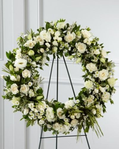 <p>Graceful and timeless, this elegant wreath offers a serene expression of sympathy and enduring love. Designed to honor a life with dignity and beauty, it speaks quietly of remembrance, comfort, and support. The circular shape represents eternity, making it a powerful symbol of connection and love that continues beyond loss.</p>
<p>Delicate white freesia, soft double lisianthus, and gentle spray roses come together in a soothing palette of soft tones and varied textures. Accents of monte casino asters and purple limonium add depth and subtle contrast, while fresh greenery provides fullness and a natural touch. A simple green raffia ribbon ties the arrangement together, adding a final note of understated elegance.</p>
<p>This wreath is a fitting tribute for memorial services, funeral homes, celebration-of-life ceremonies, or graveside settings. Its peaceful color scheme and open design create a space for reflection and remembrance, offering comfort to those who gather. The timeless form and thoughtful blooms create a respectful and meaningful expression of sympathy.</p>
<p>Whether displayed on an easel or placed at a service, the wreath offers a dignified way to share condolences. It stands as a quiet reminder of love and connection, providing a focal point for honoring memories and offering support during times of grief.</p>
<p>Each wreath is handcrafted using fresh blooms and greenery, with natural variations that make every arrangement unique. While specific flower types may vary slightly due to availability, the overall design and sentiment remain the same. Offer a gesture of comfort and remembrance with a floral tribute that speaks from the heart.</p>