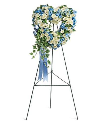 <p>Express your deepest sympathies with a tender and elegant wreath designed in the shape of a heart. Soft in color and rich in meaning, this petite 16-inch arrangement offers a graceful farewell filled with love, purity, and peace. It is a touching way to honor a special soul and provide comfort to grieving hearts.</p>
<p>This delicate design features sky blue hydrangea and snow white spray roses, carefully arranged to create a serene and soothing display. The heart-shaped frame symbolizes eternal love and devotion, while trailing variegated ivy adds gentle texture and natural beauty. Mounted on a wire easel, this wreath is ideal for display at funeral services, memorials, or graveside ceremonies.</p>
<p>Perfect for honoring someone whose spirit was kind, gentle, and full of grace, this wreath brings a sense of calm and purity to any farewell. Its compact size makes it especially suitable for intimate services or as an accent piece among larger floral tributes.</p>
<p>Each wreath is handcrafted with care and respect by compassionate florists. Same-day delivery is available to local funeral homes and service locations, ensuring your floral tribute arrives fresh, beautiful, and on time.</p>
<p>Add a personal message at checkout to accompany your gift and share heartfelt words. Send a simple yet powerful tribute that offers love and remembrance with flowers that bring comfort and meaning.</p>
