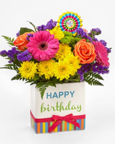 <p>Make their special day one to remember with a bouquet bursting with color, cheer, and joyful energy. This lively arrangement is designed to say “Happy Birthday” with flair, offering a radiant floral surprise that delights the senses and lifts the spirit. It’s a festive and thoughtful way to send smiles, laughter, and heartfelt wishes.</p>
<p>The bouquet features a vivid combination of hot pink gerbera daisies, purple gilly flowers, yellow chrysanthemums, orange carnations, green button poms, and sprigs of bupleurum. Every bloom is chosen for its brightness and freshness, creating a dynamic mix of texture and color that captures the excitement of a birthday celebration. The result is a lush and playful floral display that makes any space feel like a party.</p>
<p>Adding to the charm is a decorative ceramic vase, designed with colorful stripes, cheerful lettering, and a bright pink bow. This keepsake container brings even more joy to the arrangement and can be reused long after the flowers have faded. A striped birthday pick completes the look, making this bouquet a complete celebration in one thoughtful gift.</p>
<p>Perfect for friends, family, colleagues, or anyone who deserves a birthday filled with beauty and fun, this bouquet fits effortlessly into any setting. Whether it’s placed on an office desk, kitchen table, or breakfast nook, it brings festive flair and lasting cheer. It’s more than just flowers—it’s a party-ready gesture that shows how much you care.</p>
<p>Let this vibrant bouquet help make their birthday unforgettable. With its bold colors, joyful styling, and thoughtful presentation, it delivers warm wishes and happy memories, creating a moment they’ll cherish long after the candles have been blown out.</p>