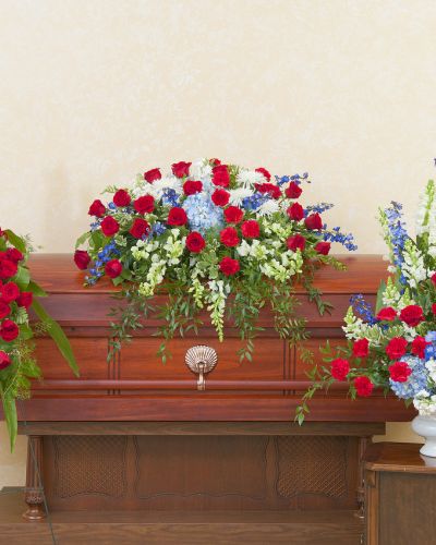 <p>Honor a proud life of service, sacrifice, and dedication with a floral tribute that reflects true spirit. This patriotic trio offers a powerful expression of remembrance, presenting a unified set of arrangements in red, white, and blue to celebrate a beloved veteran, public servant, or patriot.</p>
<p>The coordinating tribute includes a patriotic casket spray, a standing spray, and an urn arrangement—each handcrafted with fresh red roses, white lilies, blue delphinium, and other seasonal blooms. The bold color palette and structured design create a cohesive and dignified presence for any memorial service.</p>
<p>Perfect for families honoring a loved one who served in the military or devoted their life to country and community, this trio represents courage, loyalty, and enduring gratitude. It offers a heartfelt way to say goodbye while honoring the values held dear.</p>
<p>Each piece is lovingly created by expert florists who ensure every tribute arrives fresh, full, and respectfully presented. Attention to detail and thoughtful care are priorities in crafting a lasting memorial.</p>
<p>Add a message of remembrance to personalize your tribute. This patriotic trio sends a lasting symbol of honor, pride, and heartfelt appreciation.</p>