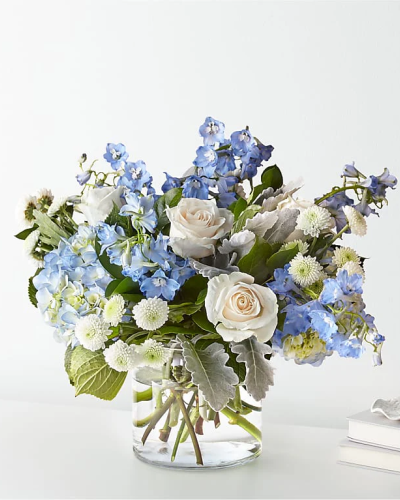 <p>Bring calm and comfort into any moment with the Clear Skies Bouquet—a peaceful arrangement inspired by the gentle beauty of a bright, cloudless day. With its soft blue tones, pure white blooms, and fresh greenery, this design offers a graceful way to express support, encouragement, or heartfelt sympathy.</p>
<p>This soothing bouquet features pale blue flowers—such as hydrangea or delphinium—paired with crisp white roses and a lush mix of greenery. The delicate balance of color and texture creates a soft, airy presentation that feels refreshing and refined. Arranged in a simple clear glass vase, the design highlights the natural elegance of each bloom while maintaining a clean, modern feel.</p>
<p>Ideal for a range of occasions, the Clear Skies Bouquet is perfect for get-well wishes, sympathy messages, new baby celebrations, or simply letting someone know they’re in your thoughts. Its tranquil color palette provides comfort during moments of reflection while bringing a gentle brightness to any space.</p>
<p>Handcrafted with care by expert local florists using the freshest seasonal flowers, this bouquet may arrive with select blooms in bud form for lasting enjoyment. Local delivery ensures your thoughtful gift arrives fresh, beautiful, and ready to offer comfort and peace.</p>
<p>Share a quiet moment of hope and serenity with the Clear Skies Bouquet—a meaningful gift of beauty and support.</p>