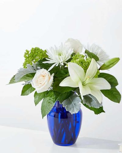 <p>Bring the quiet beauty of a winter morning indoors with the Snowy Dreams Bouquet. This elegant white arrangement captures the peaceful stillness of freshly fallen snow, offering a graceful and heartfelt way to share your warmest wishes this season. Whether you're celebrating a winter birthday, sending comfort, or simply brightening someone’s day, this bouquet conveys love, peace, and beauty in every bloom.</p>
<p>The bouquet features an all-white blend of pristine roses, soft lilies, and delicate chrysanthemums, accented with seasonal greenery for added texture and depth. Arranged in a frosted blue glass vase, the design offers a subtle contrast that enhances the snowy tones of the flowers. The result is a striking yet calming display that feels both refined and soothing.</p>
<p>Perfect for winter holidays, sympathy gestures, or quiet expressions of care, the Snowy Dreams Bouquet fits effortlessly into any space. Its serene color palette makes it ideal for moments when gentle beauty and thoughtfulness are most needed. The blue vase serves as a lasting keepsake, adding extra meaning to your gift.</p>
<p>Each bouquet is handcrafted by skilled local florists using the freshest seasonal blooms. Some flowers may arrive in bud form to ensure longer-lasting enjoyment. Local delivery is available to guarantee your gift arrives fresh and full of quiet elegance.</p>
<p>Send the Snowy Dreams Bouquet today and share a snowy daydream—timeless, tranquil, and filled with heartfelt meaning.</p>