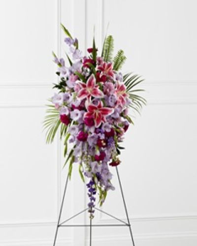 <p>When the occasion calls for elegance, reverence, and beauty, this standing spray delivers a moving tribute filled with love and light. It honors a life lived with gentleness, strength, and a vibrant spirit that touched all who knew them.</p>
<p>A stunning mix of soft purples, radiant pinks, and soothing greens creates a harmonious color blend. Featuring lavender gladiolus, fuchsia carnations, stargazer lilies, purple larkspur, Peruvian lilies, and lavender chrysanthemums, each bloom expresses sympathy, admiration, and remembrance. Sword fern and emerald palm fronds add depth and structure, giving the spray a lush, full presence.</p>
<p>Presented on a sturdy wire easel, the vertical tribute stands with quiet dignity beside the casket or memorial. Its height allows it to be seen across the room, offering comfort to grieving families and serving as a lasting symbol of beauty. The fragrance of lilies adds a subtle note of serenity.</p>
<p>This heartfelt sympathy arrangement is provided with care and detail. Same-day local delivery is available, coordinated directly with funeral homes to ensure freshness and flawless arrangement. Every order is treated with compassion and precision.</p>
<p>This standing spray is an ideal choice for expressing condolences when words fall short. Whether from family, friends, or coworkers, it speaks to the tenderness of memory and the beauty of a life well lived.</p>