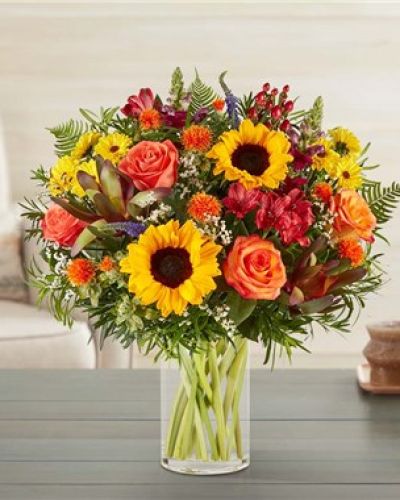 <p>Capture the warmth and richness of fall with a bouquet that brings the spirit of the season indoors. Filled with rustic textures and harvest-inspired colors, this arrangement feels like a stroll through the countryside on a crisp autumn afternoon. It’s a thoughtful gift or decorative accent that celebrates the beauty of changing leaves and cozy moments.</p>
<p>The bouquet features a radiant blend of golden sunflowers, bronze chrysanthemums, burnt orange roses, and deep red alstroemeria. Eucalyptus, solidago, and seasonal greenery add texture and depth, enhancing the natural, earthy feel of the design. The loose, garden-style composition gives it the charm of freshly gathered blooms, rich with autumn personality.</p>
<p>Arranged in a classic clear glass vase, the design strikes a perfect balance between rustic elegance and simple sophistication. The vase showcases the stems and structure of the bouquet, allowing the rich hues and organic textures to take center stage. It’s an ideal centerpiece or accent piece for fall gatherings, cozy homes, or seasonal displays.</p>
<p>Whether gifted for Thanksgiving, fall birthdays, housewarmings, or simply to share a little seasonal joy, this bouquet brings color and comfort into any space. Its inviting tones and thoughtfully layered blooms make it a memorable way to express appreciation, love, or gratitude.</p>
<p>Each bouquet is handcrafted using fresh, seasonal flowers and delivered with care. While flower types may vary slightly due to availability, the overall design and autumnal aesthetic will remain consistent. Celebrate the season with a gift that reflects nature’s most vibrant and heartwarming moments.</p>